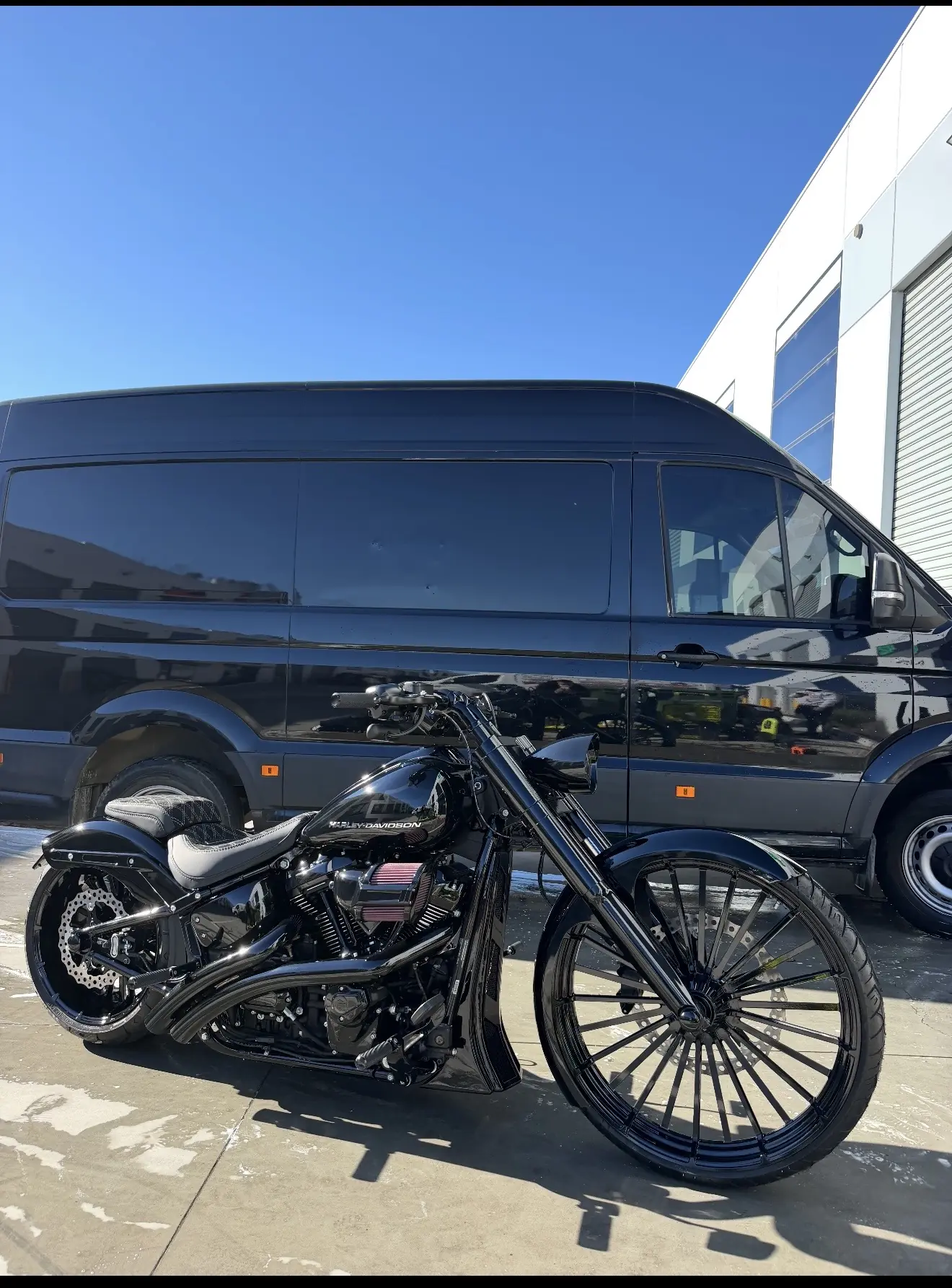 Black custom motorcycle beside the Onsite enclosed transport van